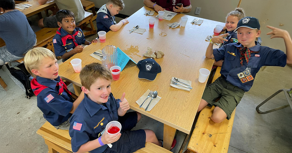 scouts sitting around a camp table in a mess hall